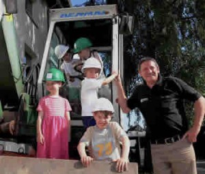 Bauunternehmer Peter vom Wege (HTS Bau GmbH) erklärt Sarah, Ben, David, Justus und Richard, wie mit dem Bagger die Außenanlagen an der Baustelle der HagenSchule in der Lützowstr. 125 umgestaltet werden.